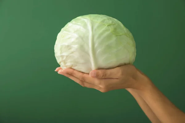 Woman holding fresh cabbage on color background