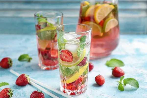 Glass of fresh strawberry lemonade on color table