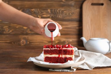 Reçel lezzetli kek parçası üzerine ahşap masanın üstüne dökülen kadın