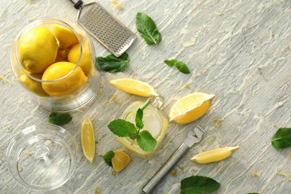 Mason jar of fresh lemonade with glass jar with citrus fruit on light table