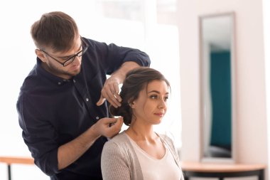 Profesyonel kuaför müşteriyle kuaförde çalışıyor.