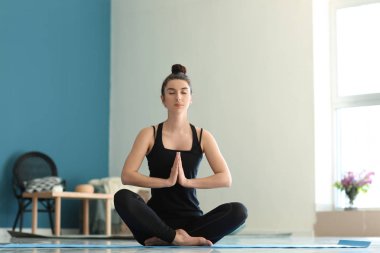 Evde yoga yapan genç bir kadın.