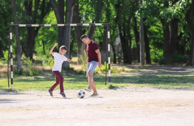 Babasıyla futbol sahada futbol oynarken küçük çocuk