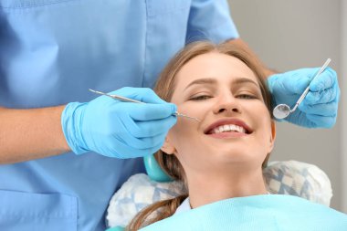 Klinikte dişçi hastanın dişlerini muayene ediyor.