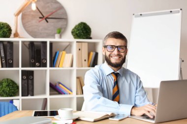 İşadamı ofiste dizüstü bilgisayarla çalışıyor.