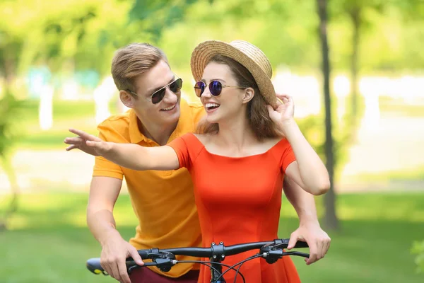 Young couple riding bicycle in park