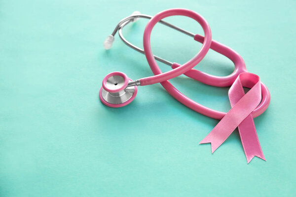 Pink ribbon and stethoscope on color background. Breast cancer awareness concept