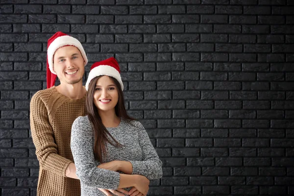 Portrait Cute Young Couple Santa Hats Dark Brick Wall — Stock Photo, Image