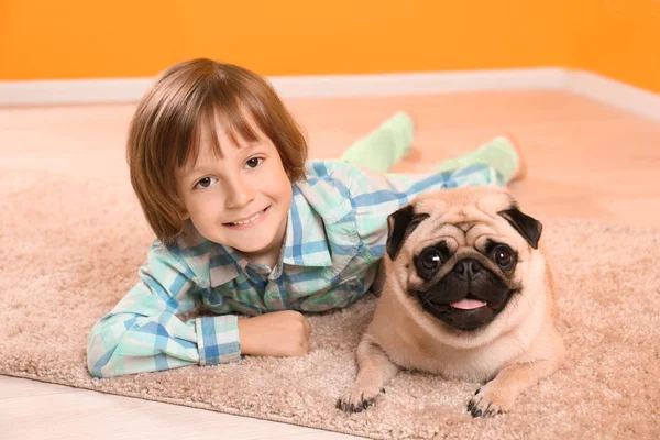 家の床の上にかわいいパグ犬と横たわっている少年 — ストック写真