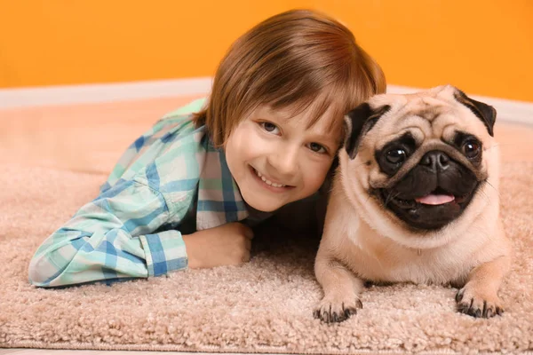 家の床の上にかわいいパグ犬と横たわっている少年 — ストック写真