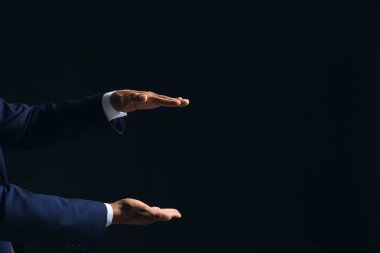 Bir şey Koyu arka plan üzerinde tutan işadamı