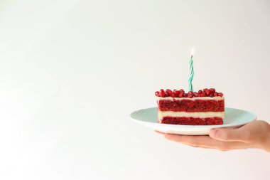 Açık renkli mum yanan ile lezzetli Doğum günü pastası parçası tutan kadın