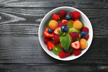 Koyu ahşap masa üzerinde kase lezzetli meyve salatası