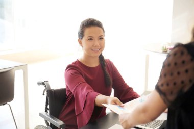Asyalı kadın meslektaşım Office ile çalışan tekerlekli sandalyede