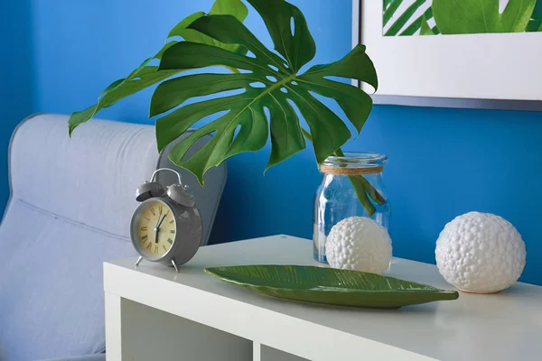 Daun Tropis Vas Kaca Dengan Jam Alarm Atas Meja Dekat — Stok Foto