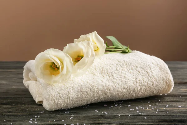 Soft towel with flowers on wooden table