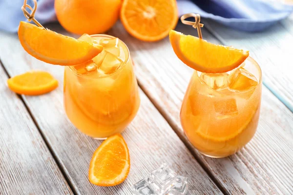Glasses of tasty orange cocktail on light wooden table