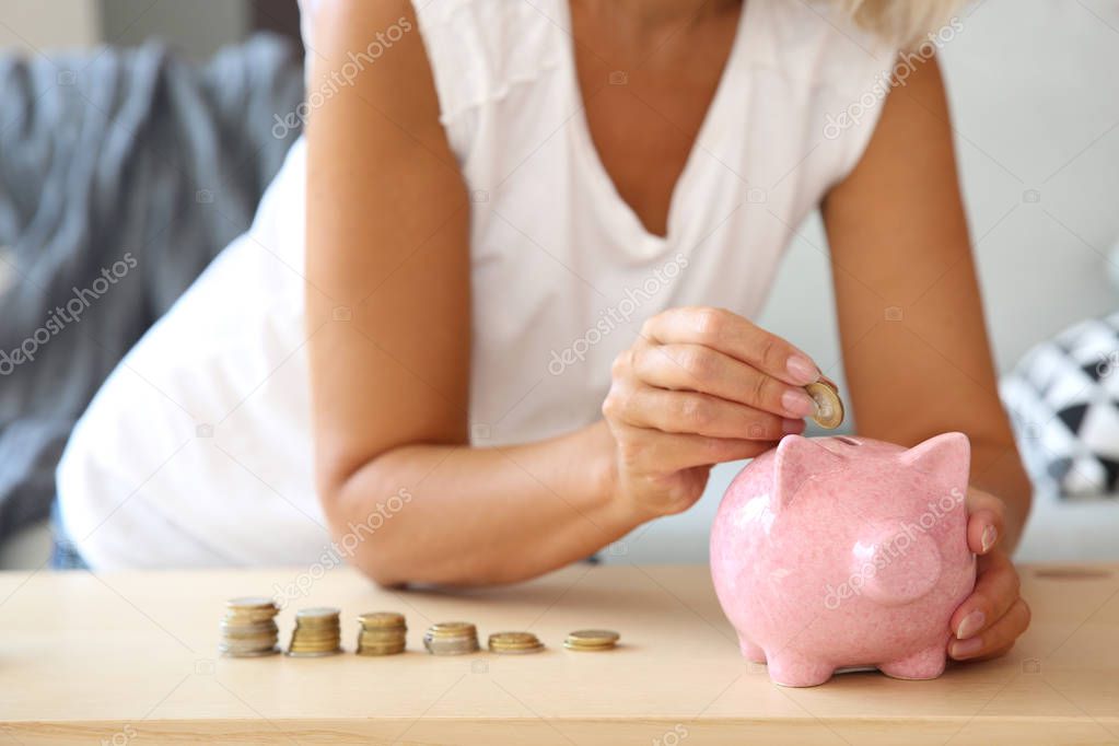 Mature woman with piggy bank counting money at home