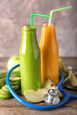 Malzemeler ve ahşap masa üzerinde stetoskop ile lezzetli smoothies şişe. Diyet kavramı