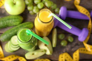 Malzemeler, halter ve ahşap masa üzerinde ölçüm bandı ile lezzetli smoothies şişe. Diyet kavramı