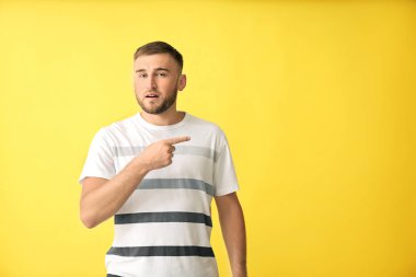 Renk arkaplanındaki bir şeye işaret eden yakışıklı adam