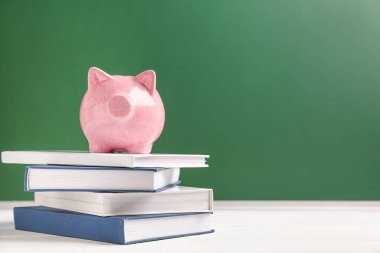 Kitap renk arka plan karşı yığını üzerinde şirin kumbara