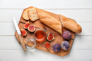 Kavanoz bal ve ahşap tahta üzerinde ekmek ile taze olgun incir