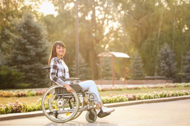 Açık havada tekerlekli sandalyede mutlu genç kadın