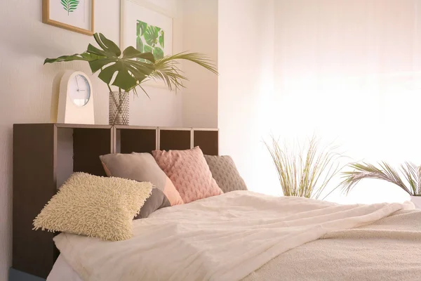 Comfortable bedroom with green tropical leaves