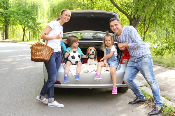 Happy family with beagle dog near car outdoors