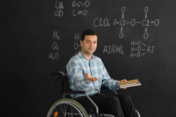 Kara Tahta Yakınındaki Tekerlekli Sandalyede Kitaplarla Erkek Öğretmen — Stok fotoğraf