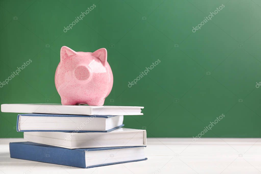 Cute piggy bank on stack of books against color background