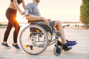 Sportif kadın genç adam açık havada tekerlekli sandalyede yardım