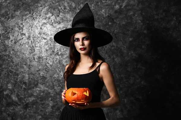 美しい女性は 暗い背景にハロウィーンの魔女に扮した — ストック写真