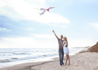 Mutlu genç çift uçan uçurtma deniz kenarında