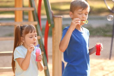 Sevimli küçük çocuklar açık havada sabun köpüğü üfleme