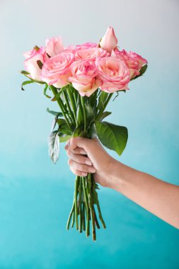 Güzel gül buketi renk arka plan üzerinde tutan kadın