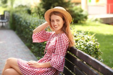 Açık havada tahta bankta oturan güzel genç kadın