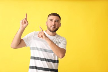 Renk arkaplanındaki bir şeye işaret eden yakışıklı adam