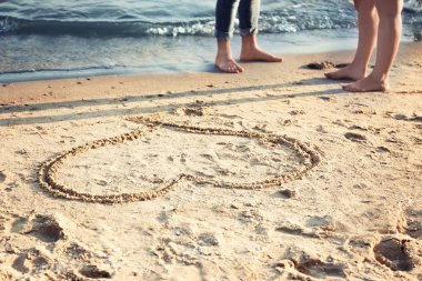 Sevimli Genç çift ve plaj kum üzerine çizilmiş kalp