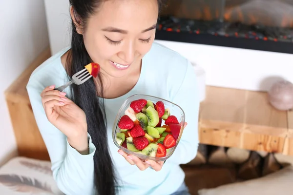 Asian woman eating healthy fruit salad at home