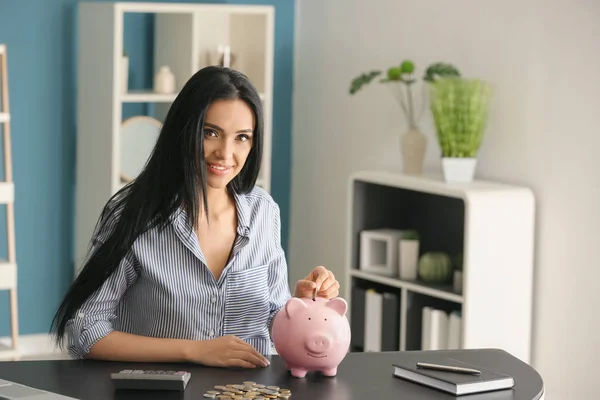 Mujer Joven Poniendo Dinero Alcancía Mesa —  Fotos de Stock