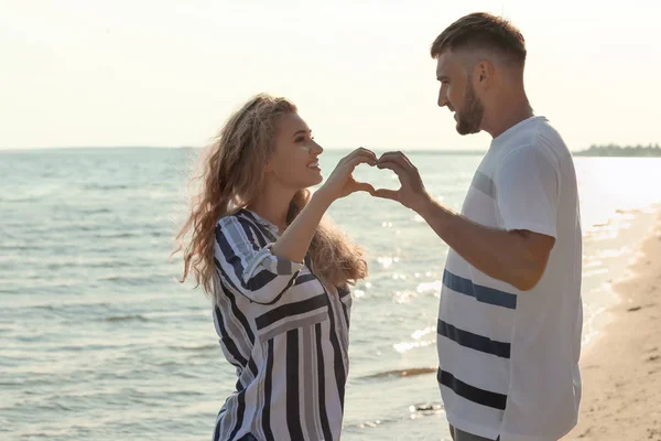 Cute Young Couple Making Heart Hands Sea Shore — Stock Photo, Image