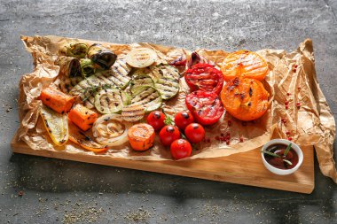 Lezzetli ızgara sebzeler ve sos gri masada ahşap tahta