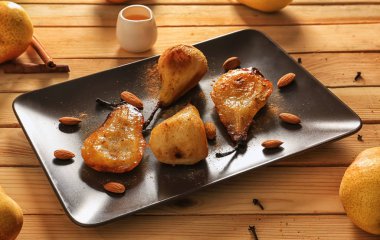 Plaka ile ahşap masa üzerinde lezzetli pişmiş armut