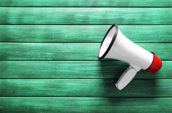 Megaphone on color wooden background