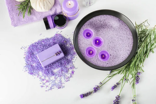 Bowl with candles and bath products on white background