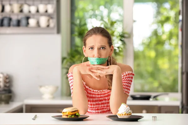 感情的な女性彼女の口とキッチンの不健康な食品の周りのテープを測定します ダイエットの概念 — ストック写真