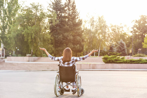 Happy young woman in wheelchair outdoors