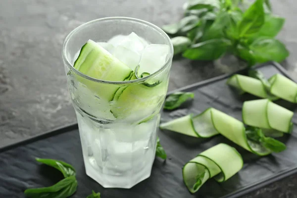 Glass of cucumber infused water with ice on table